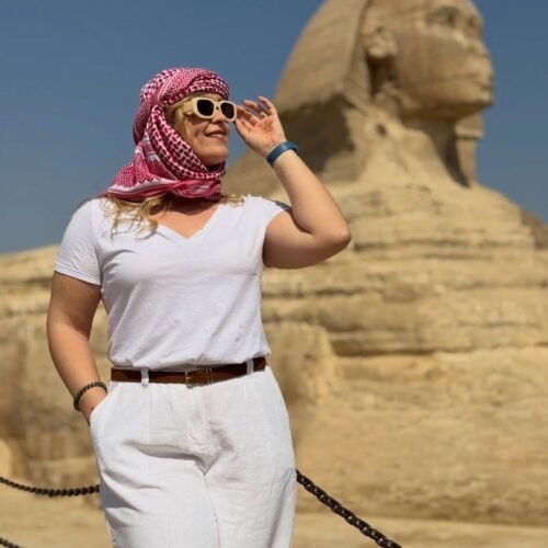 Traveler in a red-and-white keffiyeh smiling in front of the Great Sphinx on the Giza Plateau