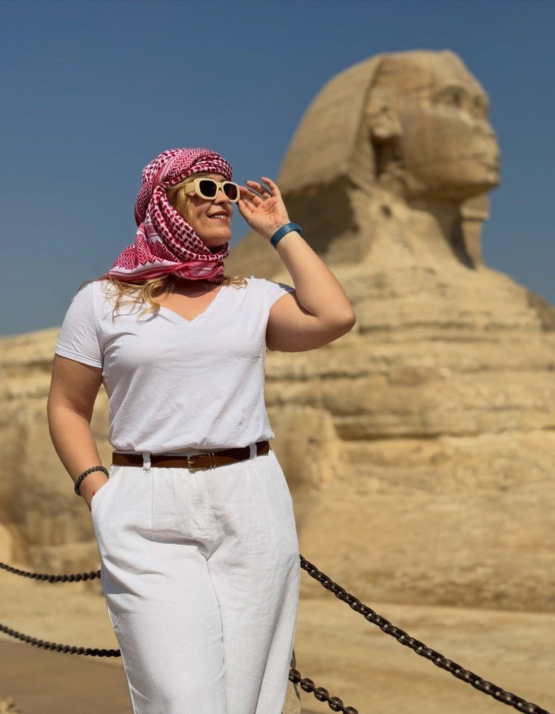 Traveler in a red-and-white keffiyeh smiling in front of the Great Sphinx on the Giza Plateau