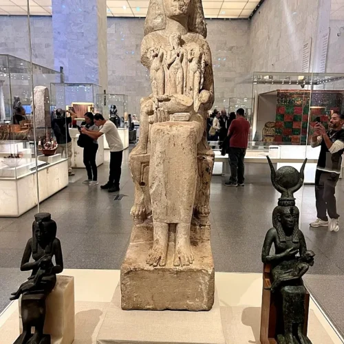 Seated mother-and-child statues including an Isis nursing figure displayed on pedestals at NMEC