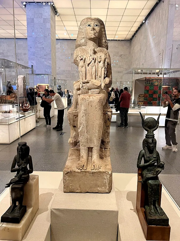 Seated mother-and-child statues including an Isis nursing figure displayed on pedestals at NMEC