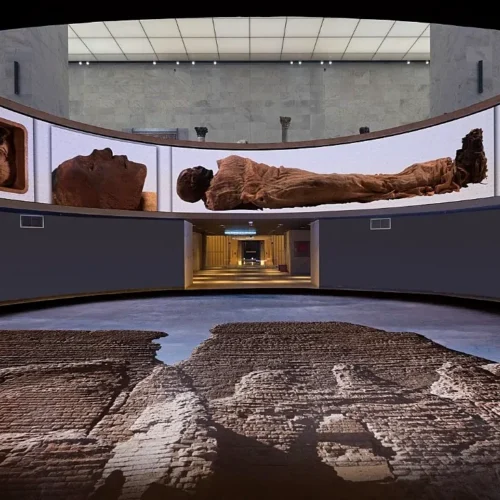 Curved interpretive wall in NMEC showing large photographs of royal mummies above a reconstructed excavation floor