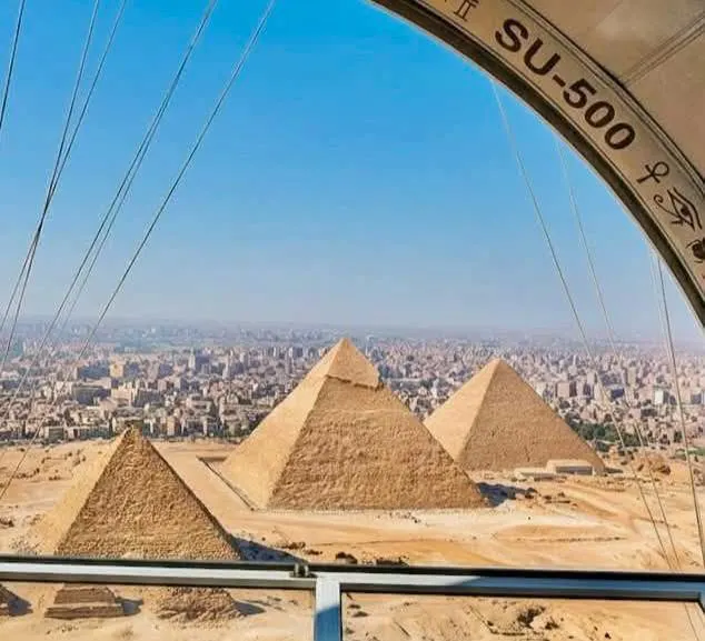 View from a tethered-balloon gondola marked SU-500 looking down at the three Giza pyramids