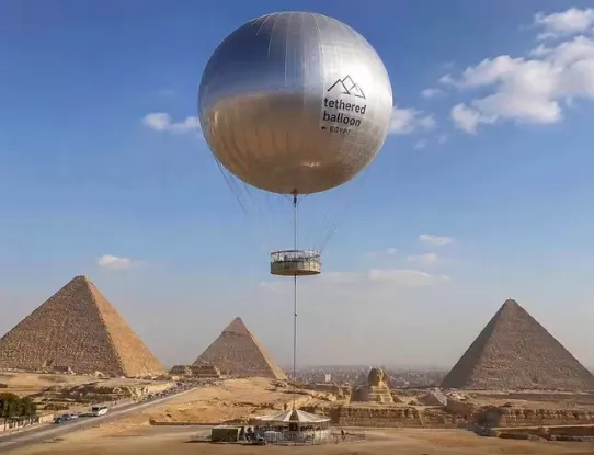 Silver tethered balloon labeled tethered balloon Egypt above the Giza Pyramids and Great Sphinx
