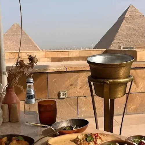 Close table setting of mezze bowls at Khufu Restaurant with two Giza pyramids beyond the limestone terrace wall