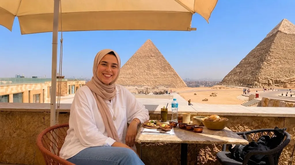 Traveler in a pink hijab dining on the Khufu Restaurant terrace with Khufu and Khafre pyramids in the background