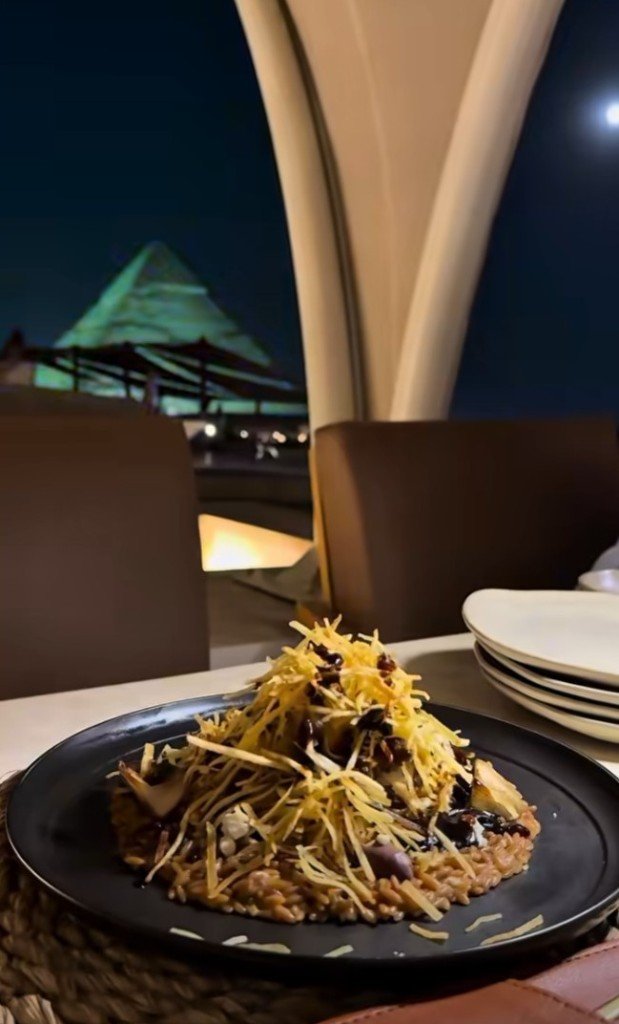 A plated rice dish, with a green-lit pyramid seen through a restaurant arch at Giza.